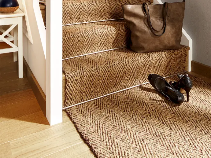 Photo of the end of a white wooden staircase with a natural-brown colored coir runner on it.