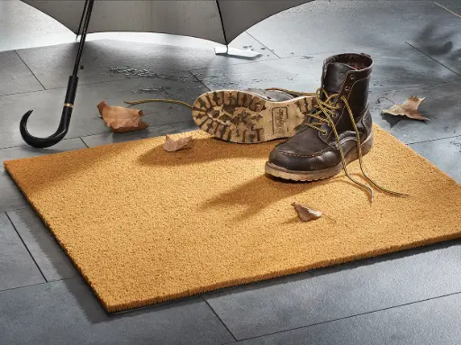 Photo of a coir doormat with two boots on it.