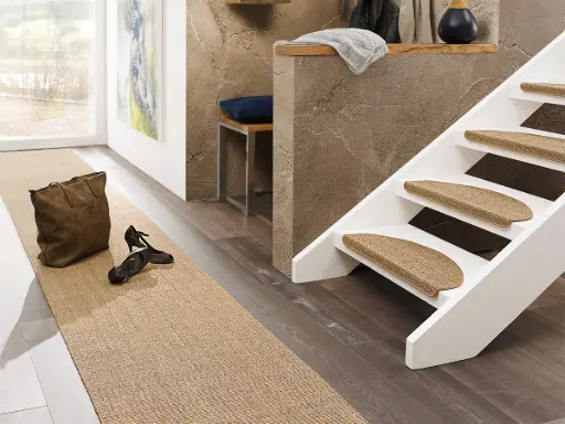 Photo of a hallway with stairs and a sisal runner and sisal stair mats in color Nut.